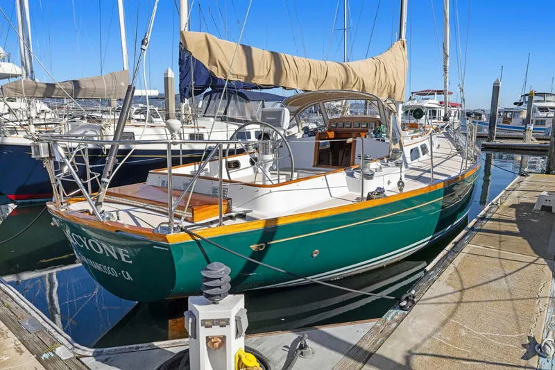 The Image of 1987 Hinckley Sou'wester 42 sailboat docked at marina, green hull, tan sail cover. - 0