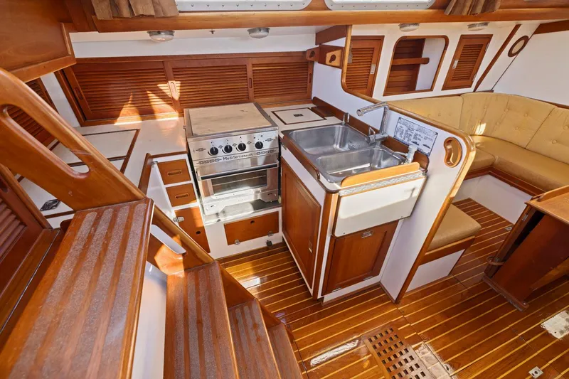 Slide: The Image of Interior of 1987 Hinckley Sou'wester 42 yacht, featuring wooden cabinetry and compact kitchen area. - 32