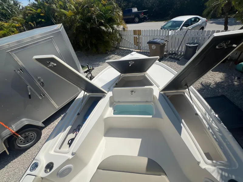 Slide: The Image of 2021 Key West 210 Bay Reef boat with open storage compartments, parked near a trailer. - 11
