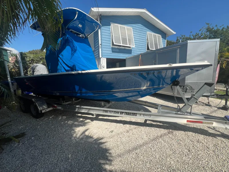Slide: The Image of 2021 Key West 210 Bay Reef boat on trailer, parked near a blue house. - 6
