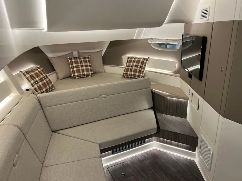 Slide: The Image of 2025 Sea Ray Sundancer 370 OB interior with modern seating, plaid pillows, and mounted TV. - 32