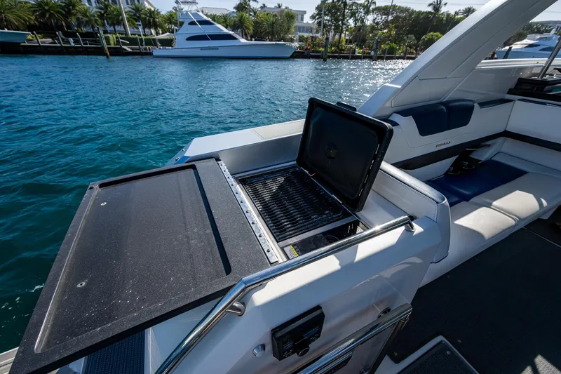 Slide: The Image of 2021 Formula 380 Super Sport Crossover OB with onboard grill, docked by a scenic waterfront. - 28