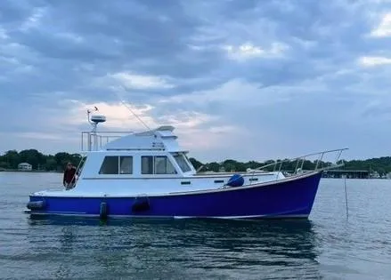 The Image of 1990 Pettegrow 36 Flybridge boat on calm water under cloudy sky. - 0