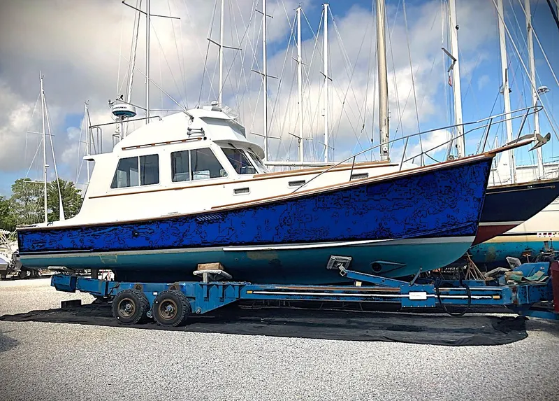 Slide: The Image of 1990 Pettegrow 36 Flybridge boat on trailer, surrounded by sailboats, under a partly cloudy sky. - 16