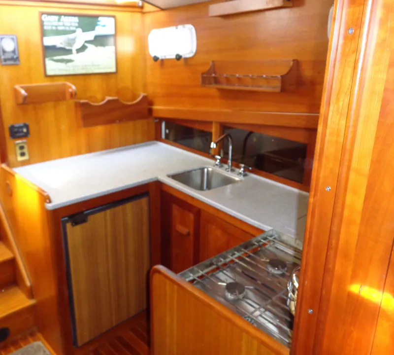 Slide: The Image of 1990 Pettegrow 36 Flybridge yacht kitchen with wood cabinetry, sink, stove, and compact fridge. - 6