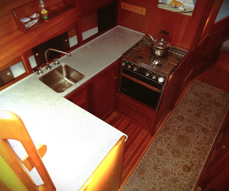 Slide: The Image of Interior of 1990 Pettegrow 36 Flybridge yacht, featuring a compact kitchen with stove and sink. - 7