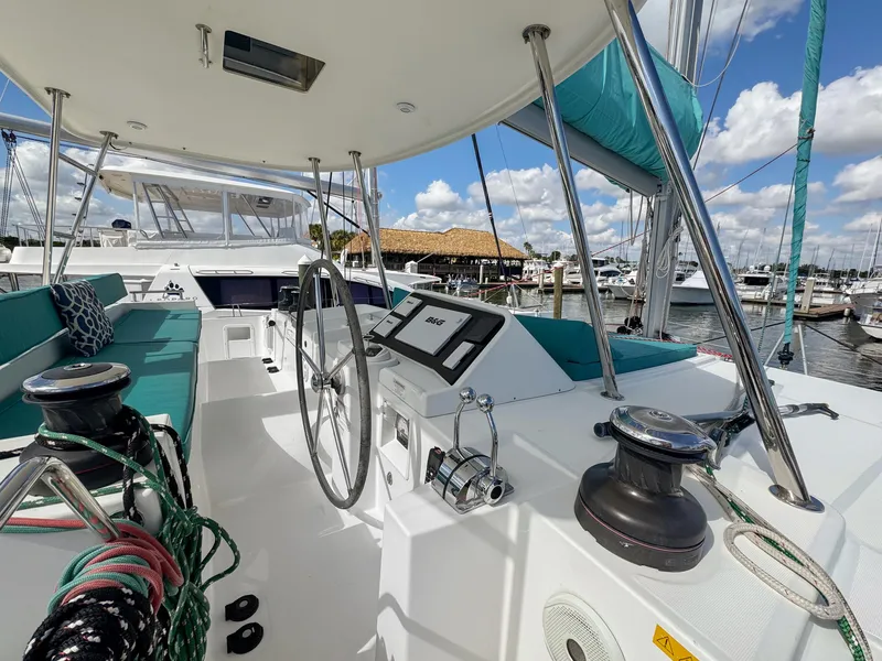 Slide: The Image of 2017 Lagoon 450 F catamaran cockpit with steering wheel, ropes, and marina view. - 16