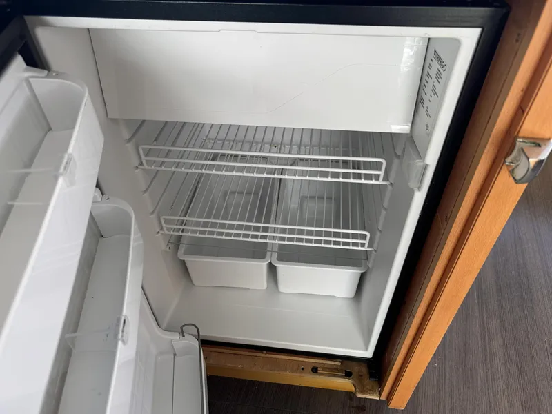 Slide: The Image of Open refrigerator inside Lagoon 450 F yacht, 2017 model, with empty shelves and storage bins. - 33