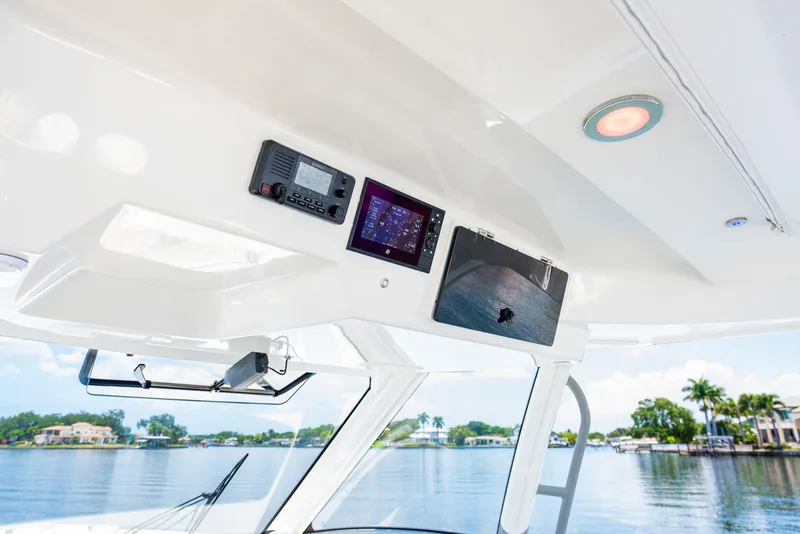 Slide: The Image of 2021 Boston Whaler 350 Realm helm with modern navigation equipment, overlooking serene waterfront. - 12