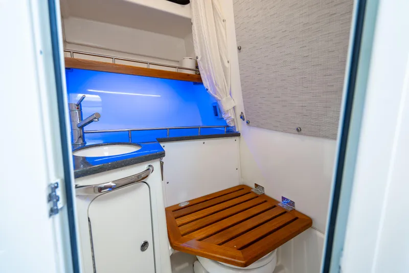 Slide: The Image of 2021 Boston Whaler 350 Realm bathroom with wooden seat, sink, and blue lighting. - 14