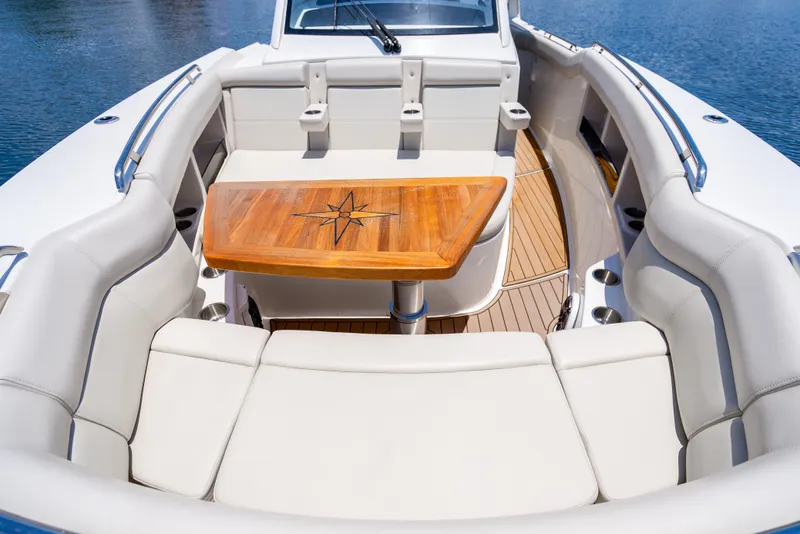 Slide: The Image of Boston Whaler 350 Realm 2021 boat interior with cushioned seating and wooden table. - 17
