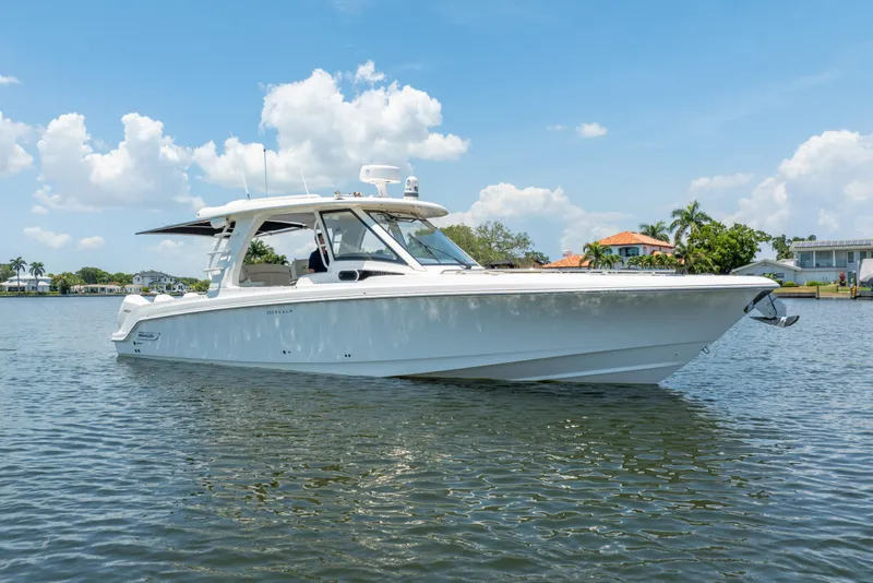Slide: The Image of 2021 Boston Whaler 350 Realm boat on calm water under a clear blue sky. - 2