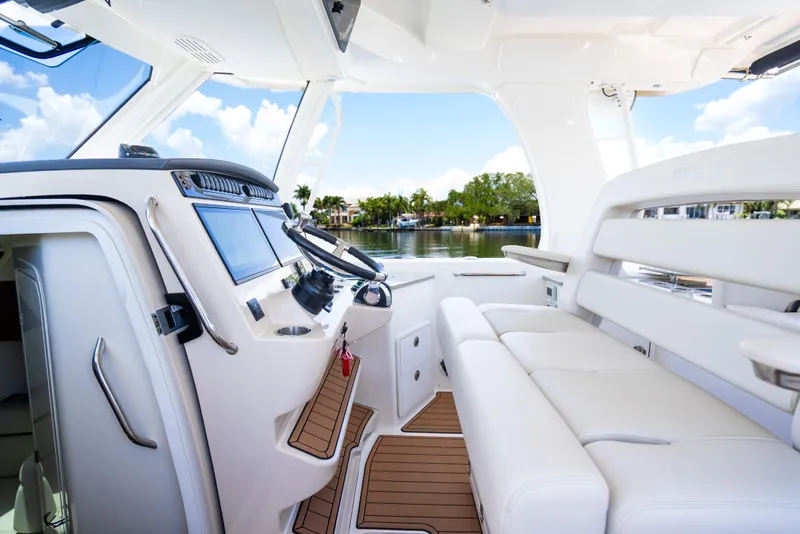 Slide: The Image of 2021 Boston Whaler 350 Realm interior with modern helm and seating, overlooking serene water. - 22