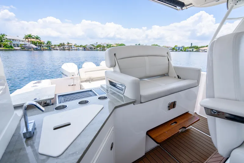 Slide: The Image of 2021 Boston Whaler 350 Realm interior with seating and kitchenette, overlooking serene waterfront. - 25