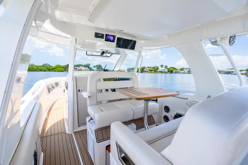 Slide: The Image of 2021 Boston Whaler 350 Realm interior with seating and table, overlooking serene waters. - 30