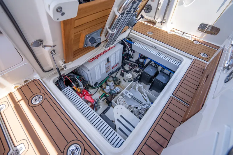 Slide: The Image of 2021 Boston Whaler 350 Realm engine compartment with batteries and equipment, featuring teak flooring. - 38