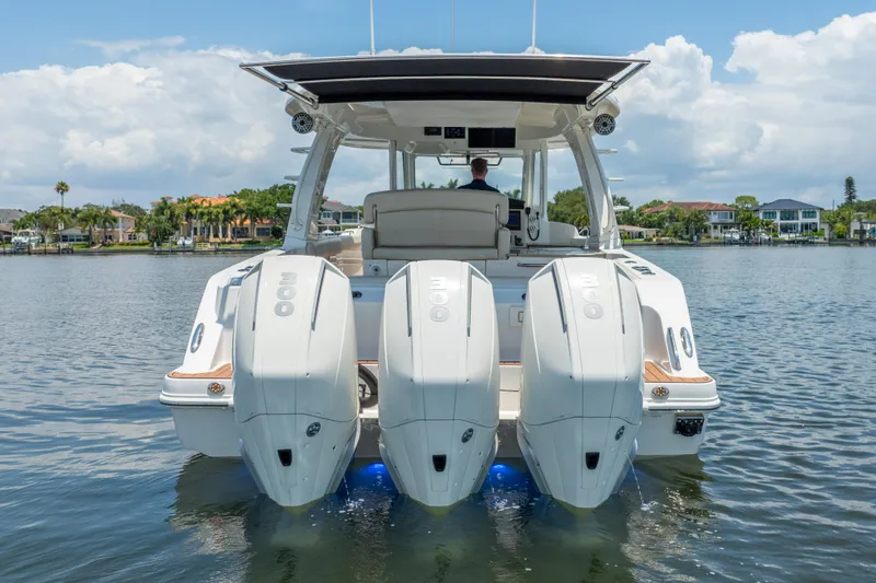 Slide: The Image of 2021 Boston Whaler 350 Realm with triple outboard engines on a calm lake. - 4