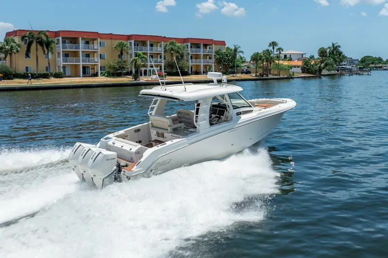Slide: The Image of 2021 Boston Whaler 350 Realm cruising on a sunny waterfront with palm trees and buildings. - 6