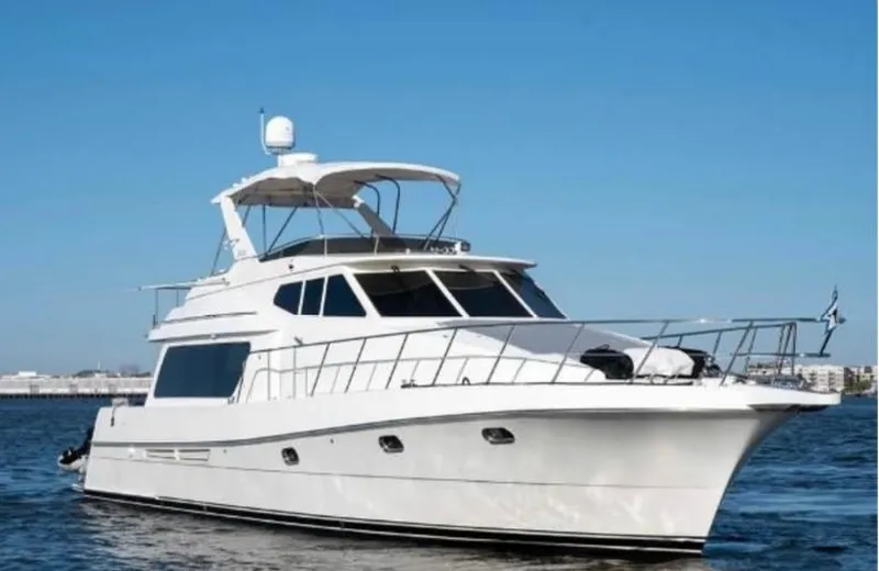 The Image of 2005 McKinna 57 Pilothouse yacht cruising on open water under clear blue sky. - 1