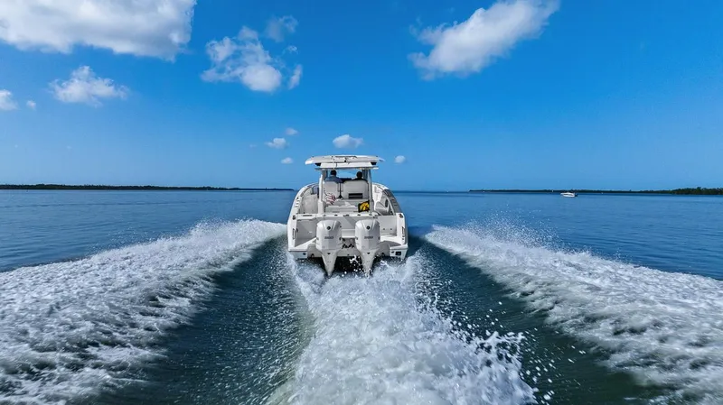 Slide: The Image of 2021 Pursuit S 328 Sport boat speeding on open water under blue sky. - 16