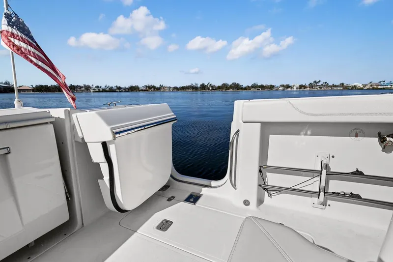 Slide: The Image of 2021 Pursuit S 328 Sport boat interior with open deck, American flag, and scenic water view. - 26