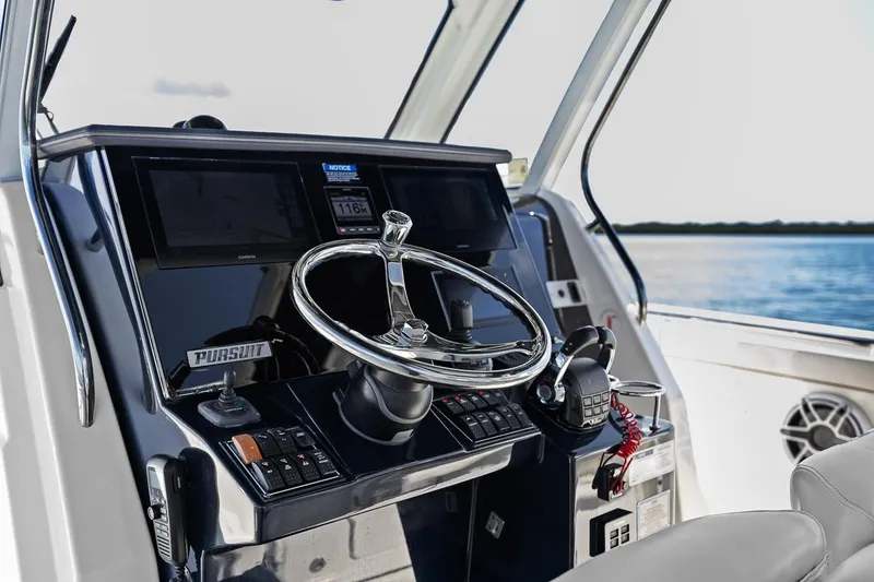 Slide: The Image of 2021 Pursuit S 328 Sport boat helm with steering wheel and controls. - 5