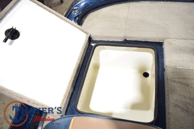 Slide: The Image of 2000 Ranger R83 boat storage compartment with open lid, featuring carpeted interior. - 27