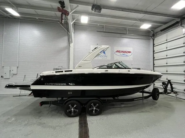 Slide: The Image of 2024 Chaparral 267 SSX boat in showroom, black and white exterior, on a trailer. - 1