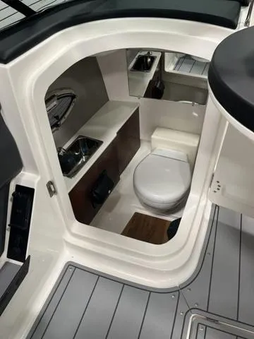 Slide: The Image of 2024 Chaparral 267 SSX boat interior with compact bathroom and modern amenities. - 15