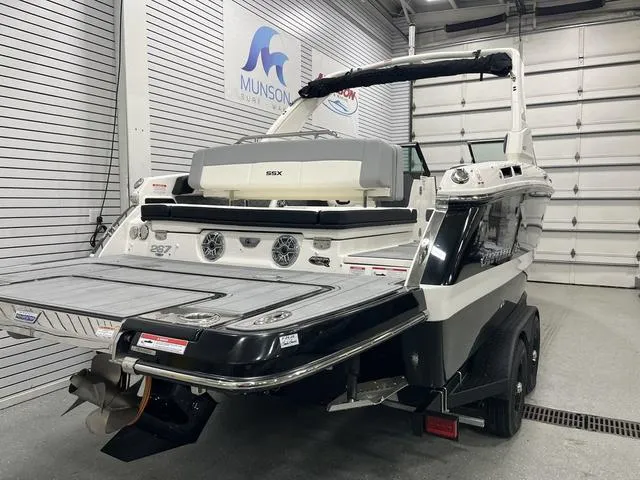 Slide: The Image of 2024 Chaparral 267 SSX boat in showroom, rear view with swim platform and trailer. - 4