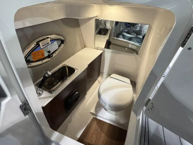 Slide: The Image of 2025 Chaparral 2870 SSX boat bathroom with sink, toilet, and mirror. - 16