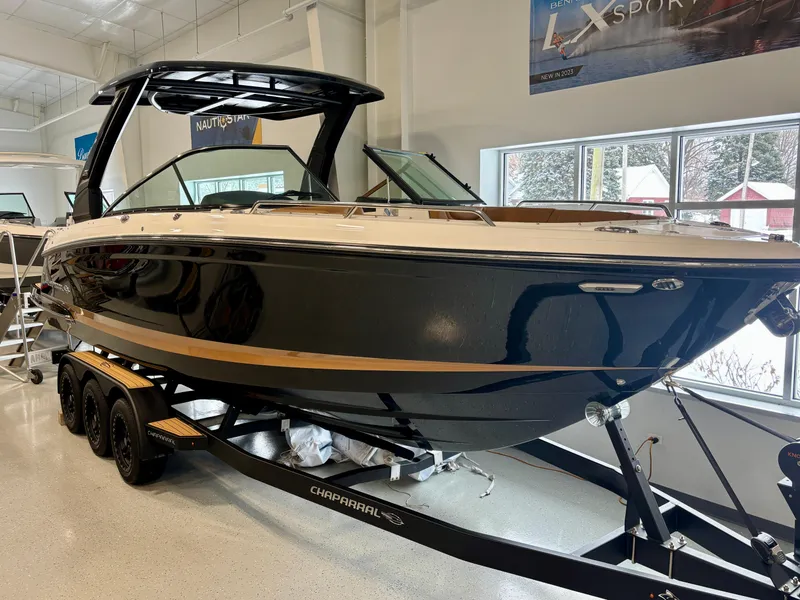 Slide: The Image of 2025 Chaparral 307 SSX boat on trailer in showroom, sleek black design. - 2