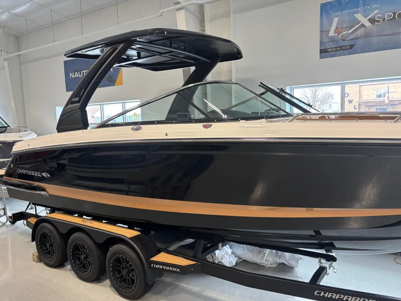 Slide: The Image of 2025 Chaparral 307 SSX boat on trailer in showroom, sleek black design. - 3
