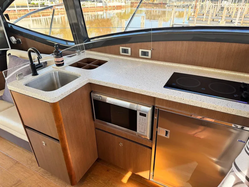 Slide: The Image of Modern kitchen area in 2016 Sea Ray 400 Sundancer yacht with sink, microwave, and stove. - 12