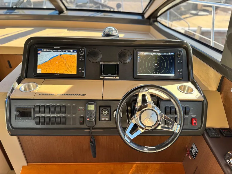 Slide: The Image of Helm of 2016 Sea Ray 400 Sundancer with navigation screens and steering wheel. - 19