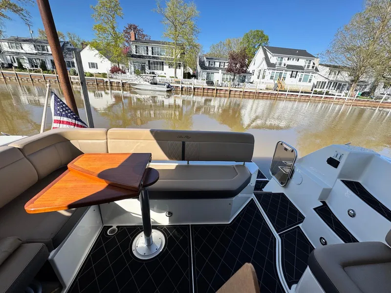 Slide: The Image of 2016 Sea Ray 400 Sundancer boat deck with seating, table, and waterfront view. - 6