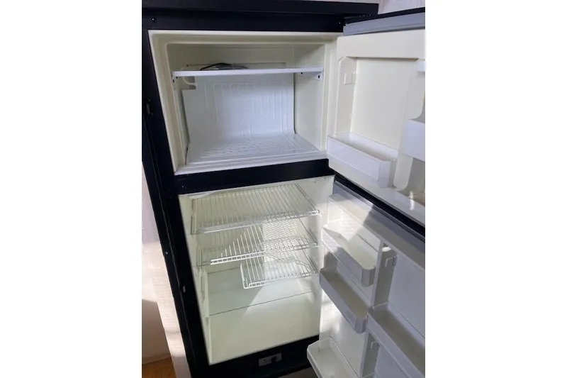 Slide: The Image of 1996 Cruisers Yachts 3650 Motoryacht refrigerator, open and empty, showing shelves and compartments. - 13