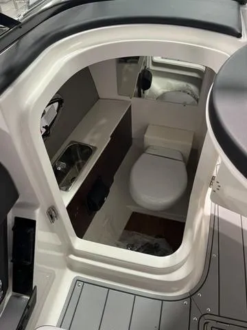 Slide: The Image of 2025 Chaparral 26 Surf boat interior bathroom with sink and toilet. - 7