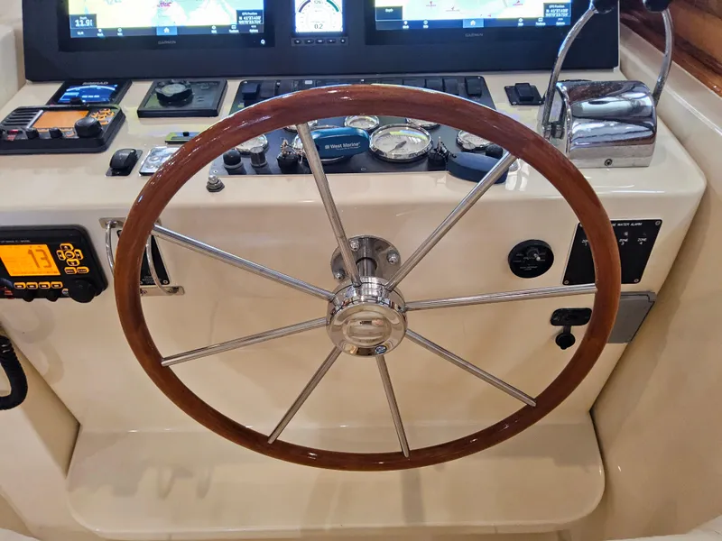 Slide: The Image of Helm of 2003 Legacy 40 Hardtop Express with wooden steering wheel and navigation instruments. - 28