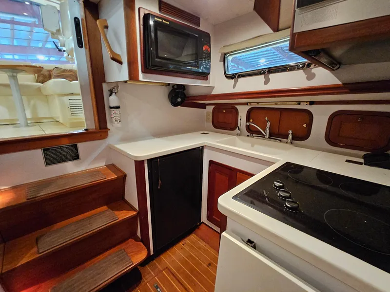 Slide: The Image of 2003 Legacy 40 Hardtop Express yacht kitchen with stove, microwave, and wooden cabinetry. - 34