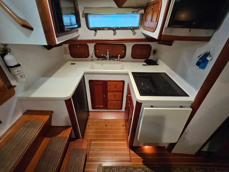 Slide: The Image of 2003 Legacy 40 Hardtop Express yacht kitchen with stove, sink, and wooden cabinetry. - 35