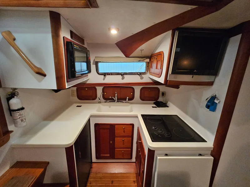 Slide: The Image of 2003 Legacy 40 Hardtop Express yacht kitchen with stove, sink, microwave, and wooden cabinetry. - 36