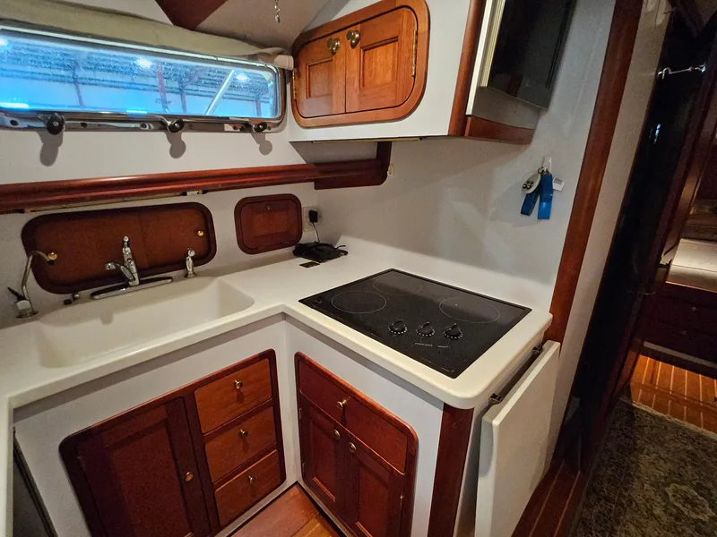 Slide: The Image of 2003 Legacy 40 Hardtop Express yacht kitchen with stove, sink, and wooden cabinetry. - 37