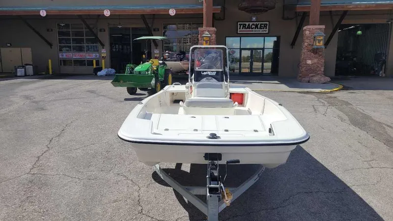 Slide: The Image of 2025 Mako Pro Skiff 15 CC boat on trailer outside a store. - 2