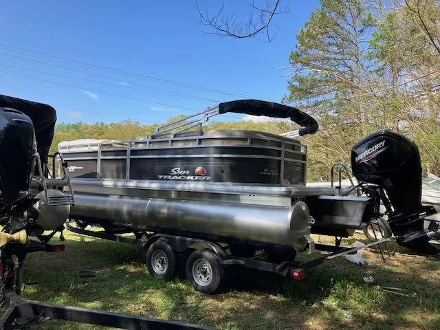 The Image of 2025 Sun Tracker Party Barge 20 DLX pontoon boat on trailer, parked outdoors. - 0