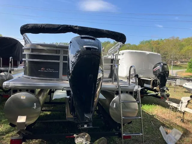 Slide: The Image of 2025 Sun Tracker Party Barge 20 DLX pontoon boat with outboard motor, parked outdoors. - 4