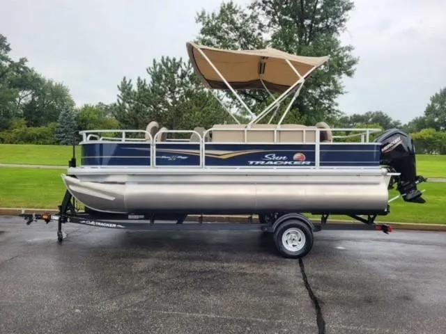 The Image of 2025 Sun Tracker Bass Buggy 18 DLX pontoon boat on trailer, parked outdoors. - 0