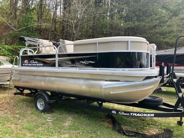 The Image of 2025 Sun Tracker Party Barge 16 DLX pontoon boat on trailer, parked outdoors. - 0