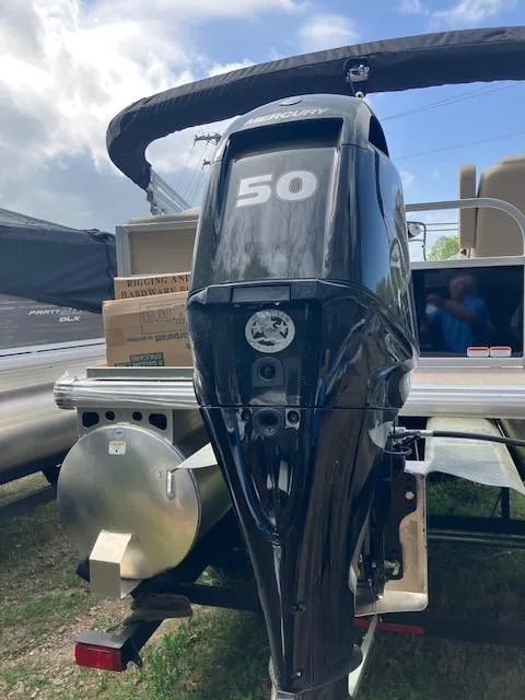 Slide: The Image of 2025 Sun Tracker Party Barge 16 DLX with 50 HP outboard motor, docked outdoors. - 4