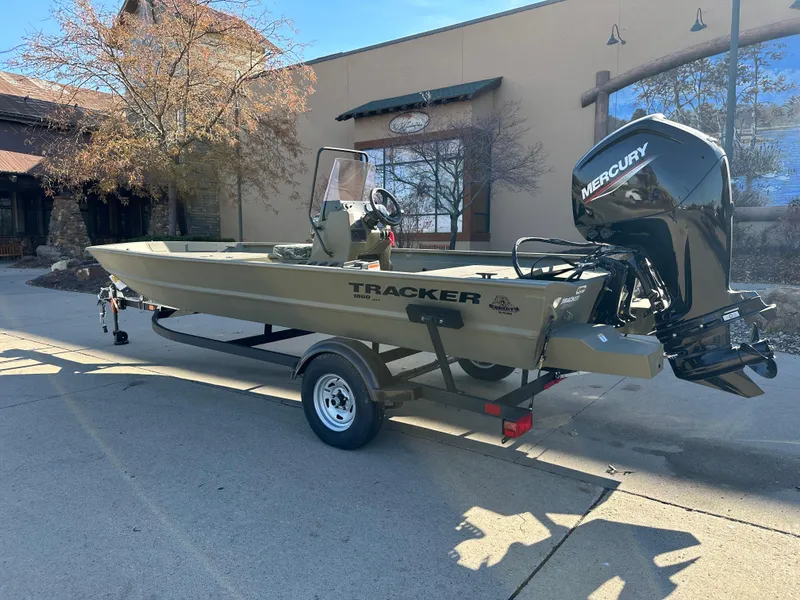 Slide: The Image of 2025 Tracker Grizzly 1860 CC boat with Mercury engine on trailer, parked outdoors. - 2